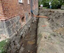 Das Fundament trocken legen Im Aussenbereich des Gutshauses wird das Feldsteinfundament bis 1,50 m Tiefe angegraben und weiter trocken gelegt.